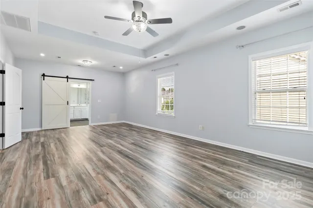 a view of empty room with wooden floor and fan