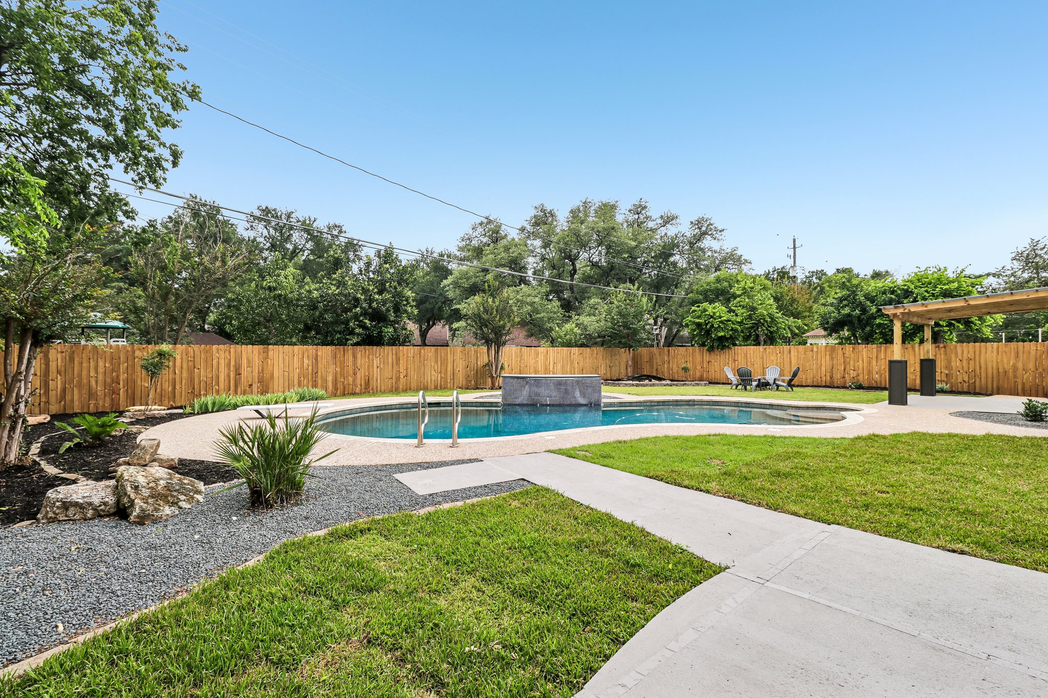 11809 Charing Cross Road Austin, TX 78759 - Photo 27 of 34 An inviting backyard oasis awaits, complete with a sparkling pool and tranquil waterfall feature.