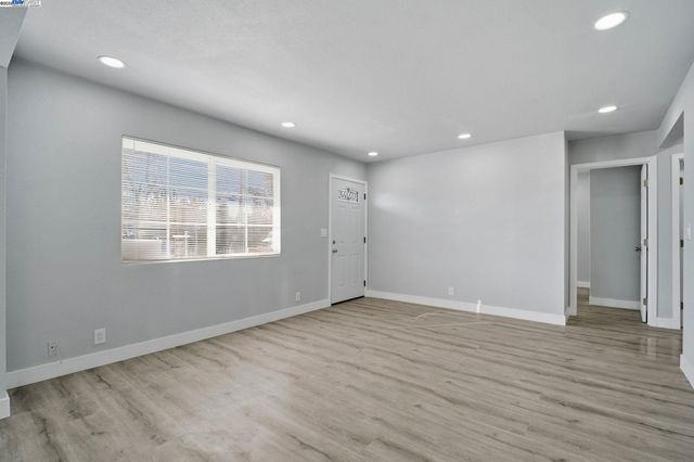 an empty room with wooden floor and natural light