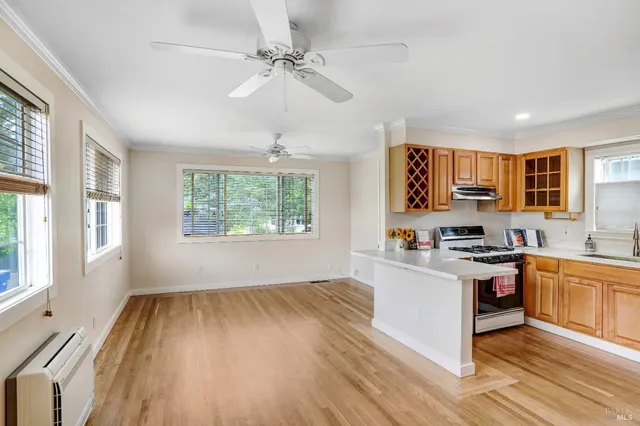 a kitchen with stainless steel appliances a stove top oven a sink dishwasher and a refrigerator with wooden floor