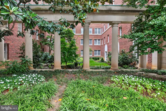 a view of a brick house with a small yard and plants