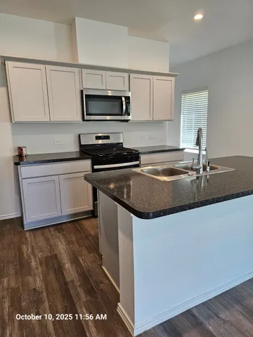 a kitchen with stainless steel appliances granite countertop a sink a stove a microwave and wooden cabinets