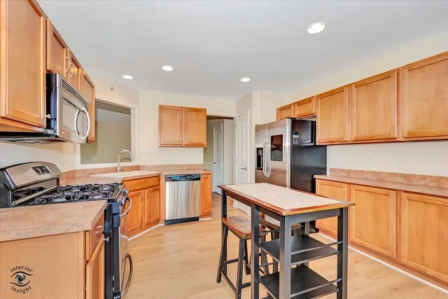 a kitchen with stainless steel appliances a stove a sink a microwave a refrigerator and cabinets