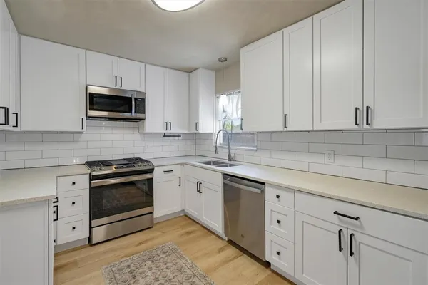 a kitchen with granite countertop white cabinets stainless steel appliances and a sink