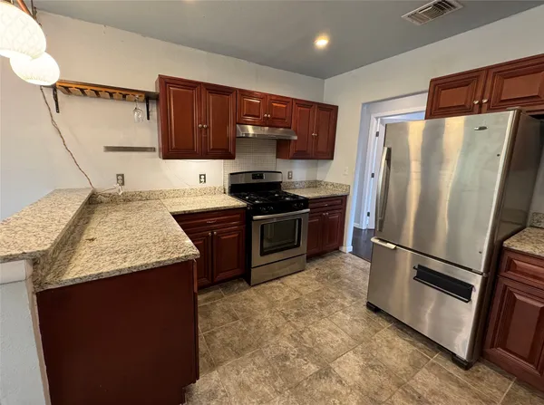 a kitchen with stainless steel appliances granite countertop a refrigerator a stove a sink and a microwave