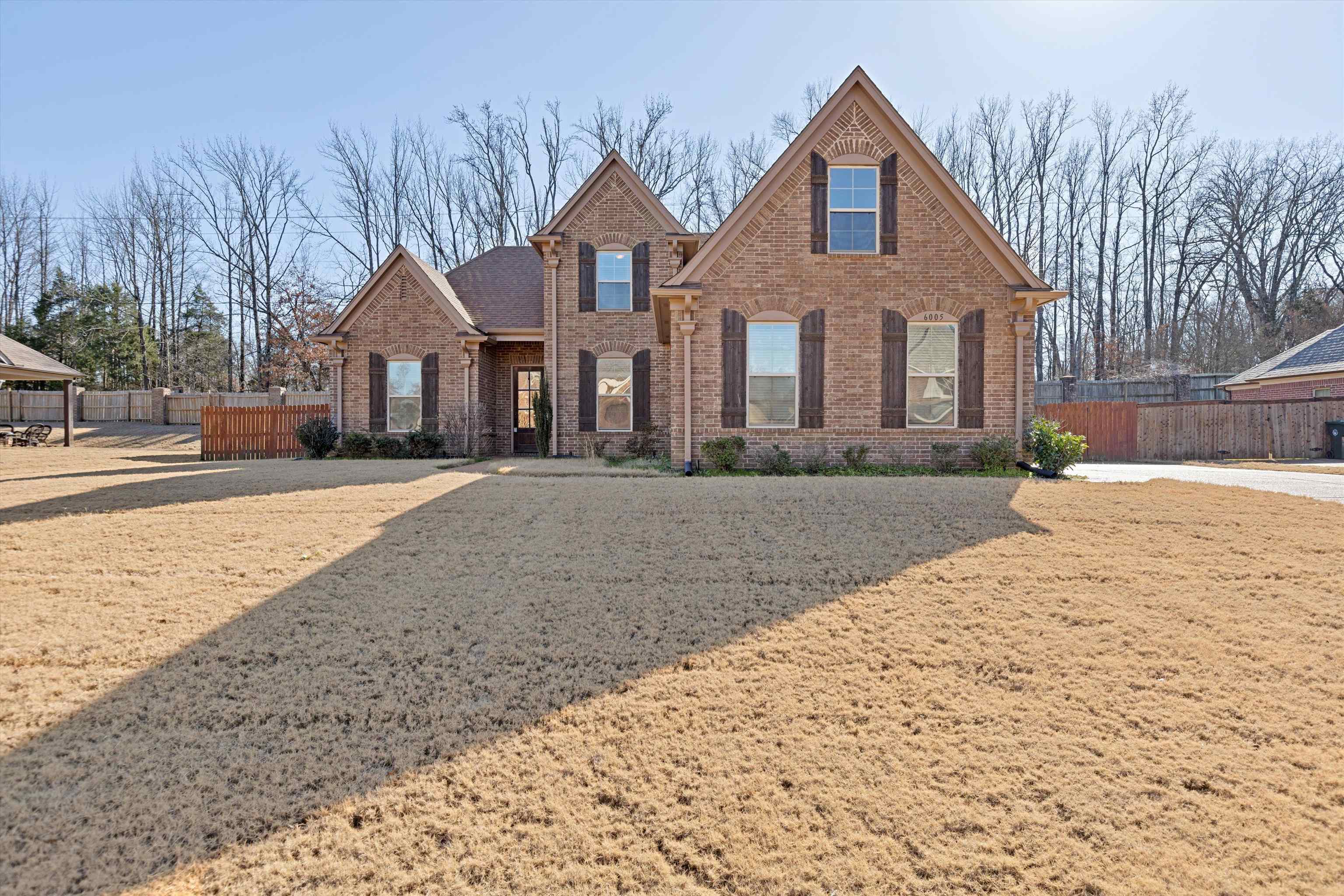 a front view of a house with a yard covered with snow and trees