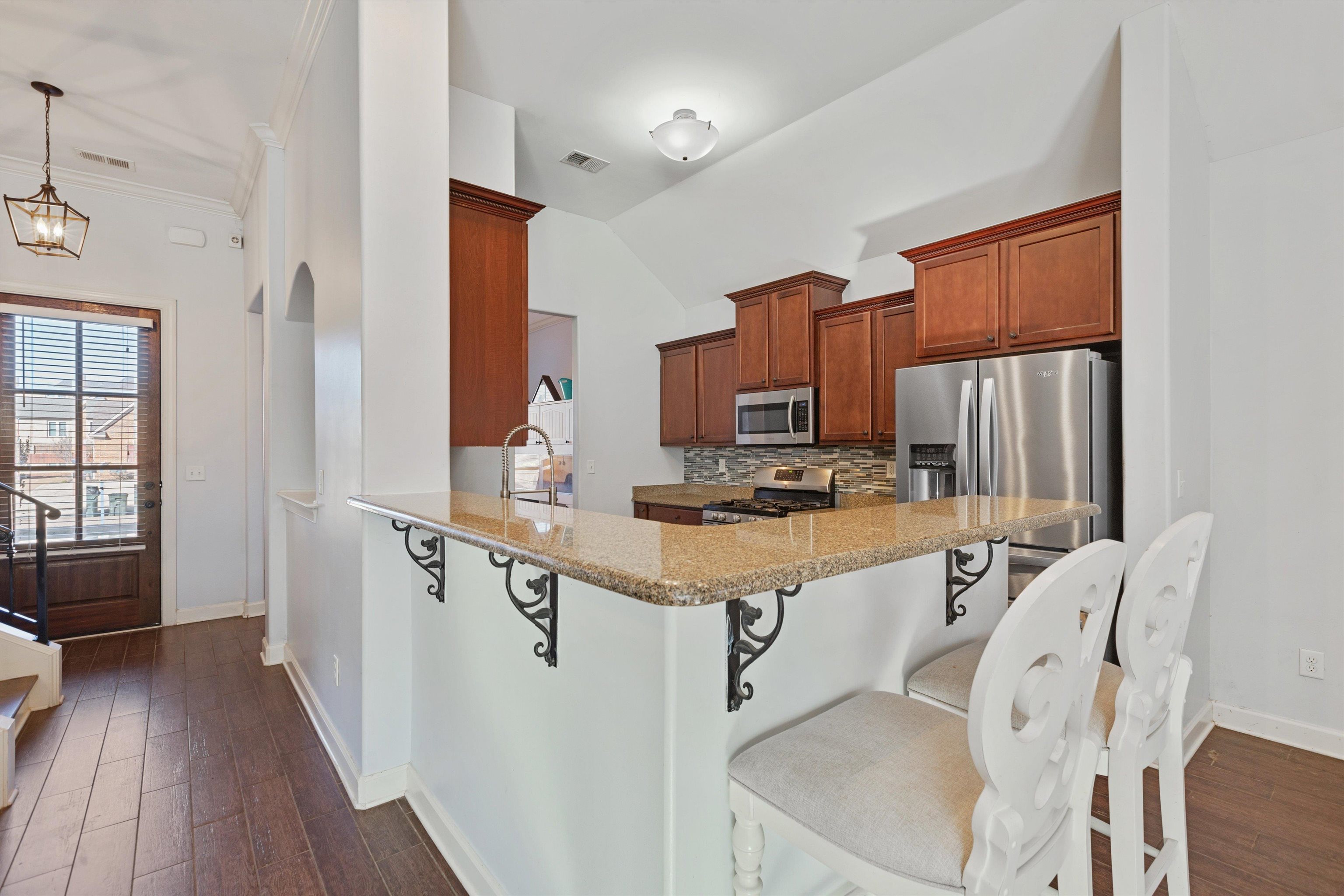 6005 Maher Valley Cove Bartlett, TN 38135 - Photo 11 of 28 a kitchen with stainless steel appliances granite countertop a sink dishwasher a refrigerator cabinets wooden floor and a dining table