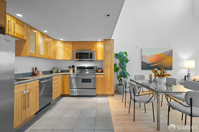 a kitchen with granite countertop stainless steel appliances a stove top oven a sink a dining table and chairs