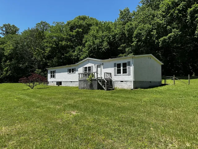 a front view of a house with a yard and trees