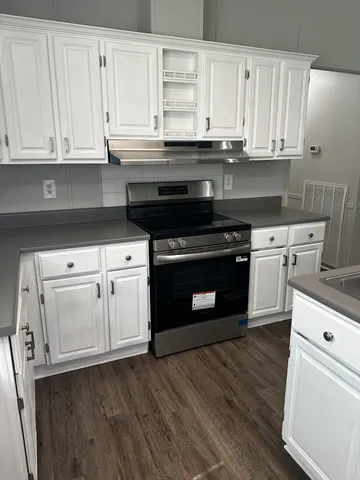 a kitchen with granite countertop a stove and a wooden floors