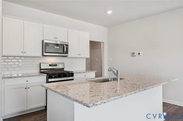 a kitchen with stainless steel appliances granite countertop a sink a stove and microwave