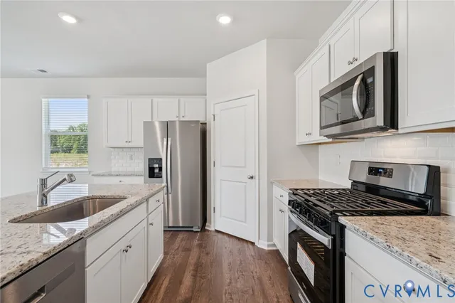 a kitchen with granite countertop a sink stove and refrigerator