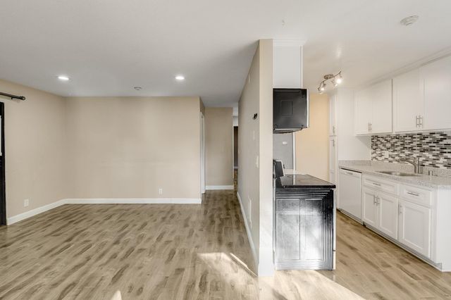 a view of an empty room with wooden floor fireplace and a window