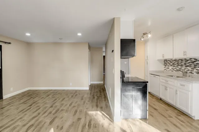 a view of an empty room with wooden floor fireplace and a window
