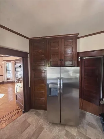 a view of a refrigerator in kitchen and an empty room