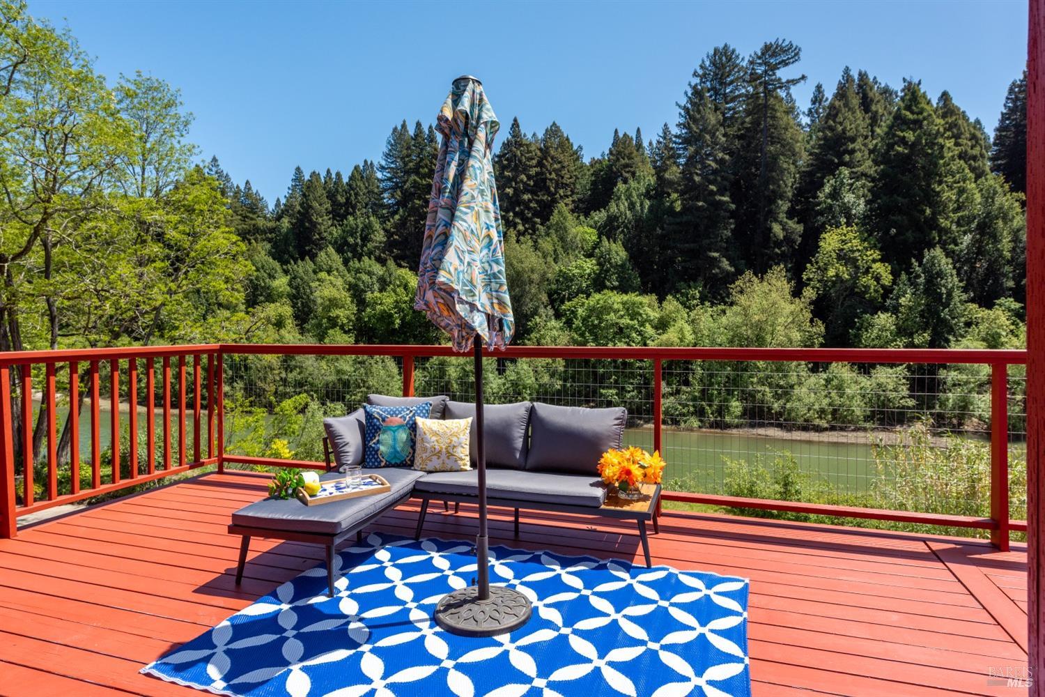 15627 Riverside Drive Guerneville, CA 95446 - Photo 21 of 41 a deck with outdoor seating and trees in the background