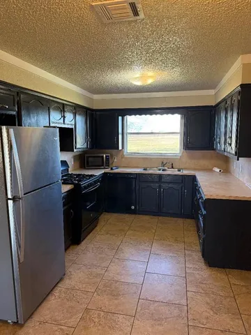 a large kitchen with granite countertop a refrigerator and a stove top oven