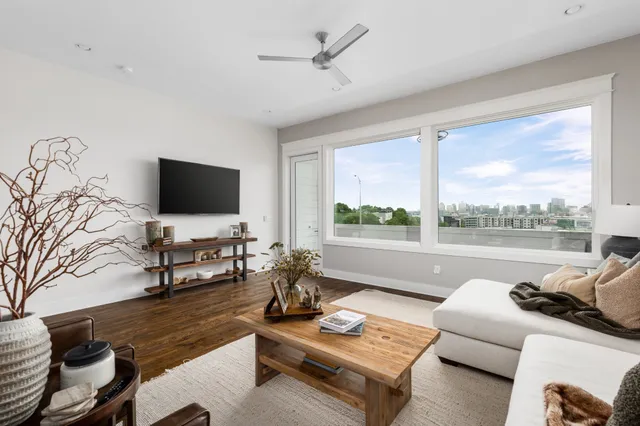 a living room with furniture a flat screen tv and a floor to ceiling window