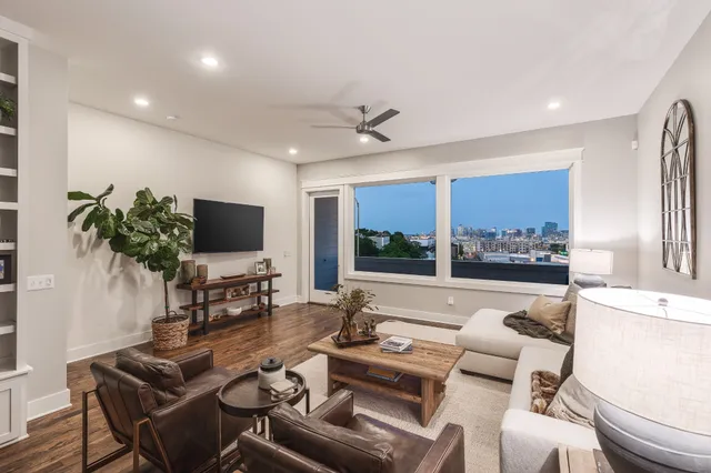 a living room with furniture a flat screen tv and a large window