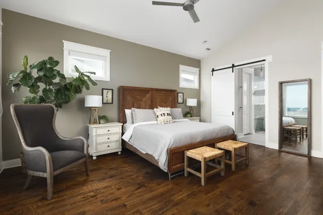 a bedroom with a bed chair and wooden floor