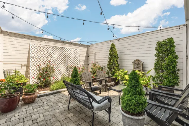 a roof deck with table and chairs and potted plants