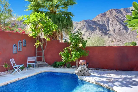 a backyard of a house with table and chairs potted plants and wooden fence