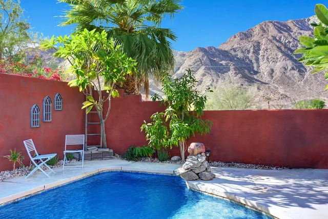 a backyard of a house with table and chairs potted plants and wooden fence