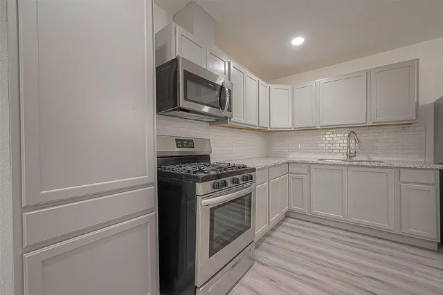 a kitchen with stainless steel appliances granite countertop a stove microwave and sink