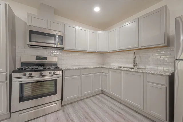 a kitchen with granite countertop a stove top oven sink and cabinets