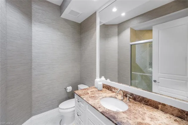 a bathroom with a granite countertop sink a toilet and a mirror