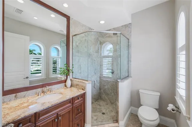 a spacious bathroom with a granite countertop sink a toilet a mirror and a window