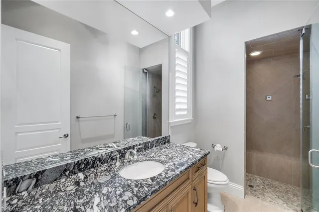 a bathroom with a granite countertop sink toilet and shower