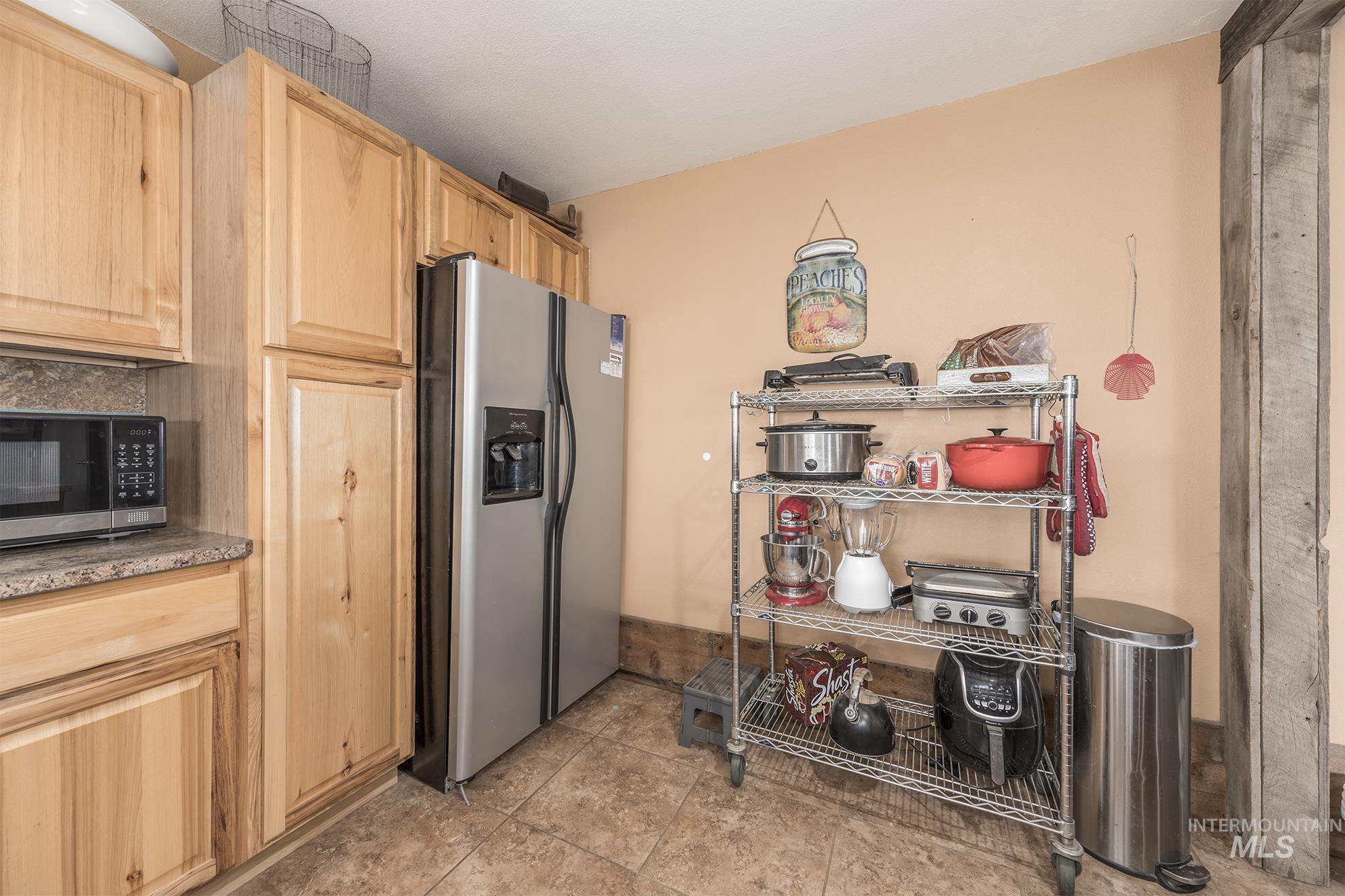 724 Mundy Gulch Road Indian Valley, ID 83632 - Photo 11 of 43 Kitchen with light brown cabinets, appliances with stainless steel finishes, light tile patterned flooring, and tasteful backsplash