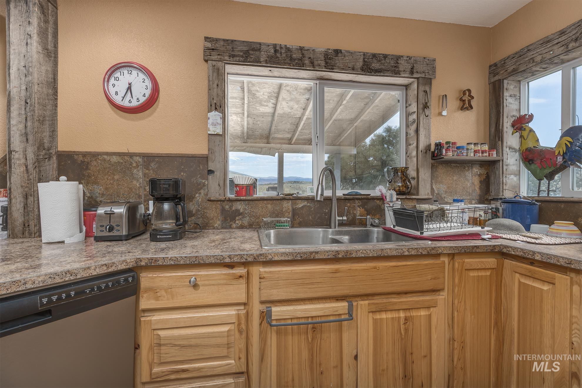 724 Mundy Gulch Road Indian Valley, ID 83632 - Photo 12 of 43 Kitchen featuring stainless steel dishwasher, healthy amount of natural light, decorative backsplash, and a textured wall
