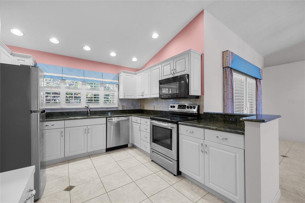 3951 Myrtle Street St. Augustine, FL 32084 - Photo 9 of 23 a kitchen with stainless steel appliances granite countertop a sink and dishwasher a stove top oven with wooden floor