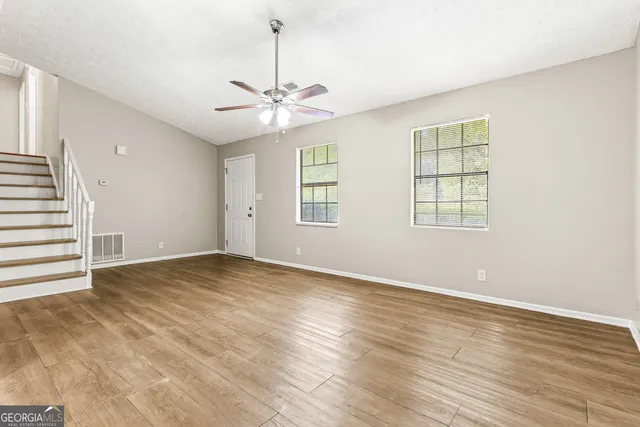 a view of an empty room with wooden floor and a window