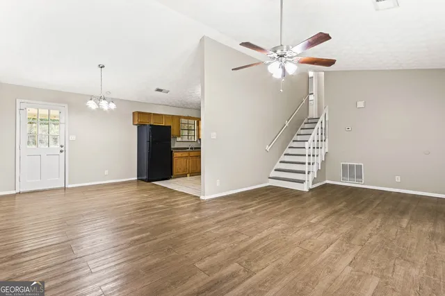an empty room with wooden floor staircase and a ceiling fan