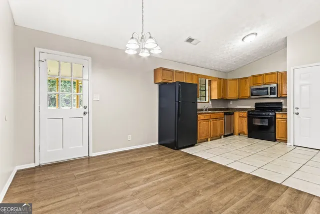 a kitchen with stainless steel appliances granite countertop a refrigerator stove top oven and cabinets