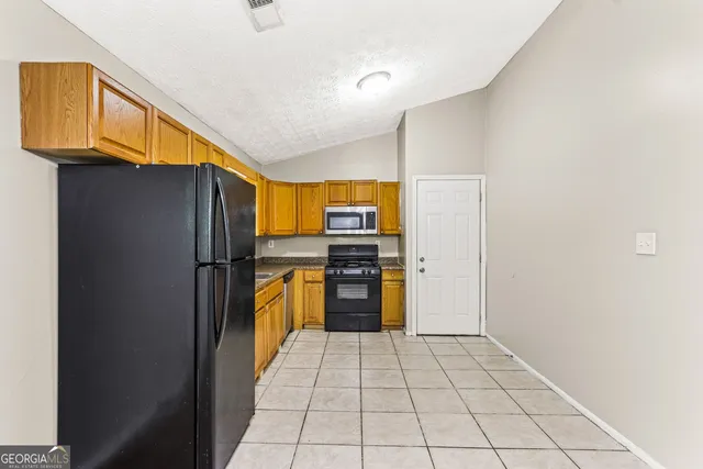 a kitchen with stainless steel appliances granite countertop a refrigerator and a stove top oven