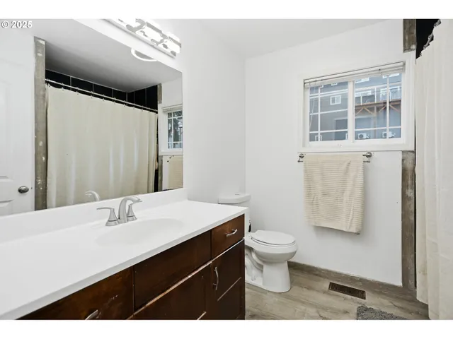 a bathroom with a sink a toilet a mirror and shower