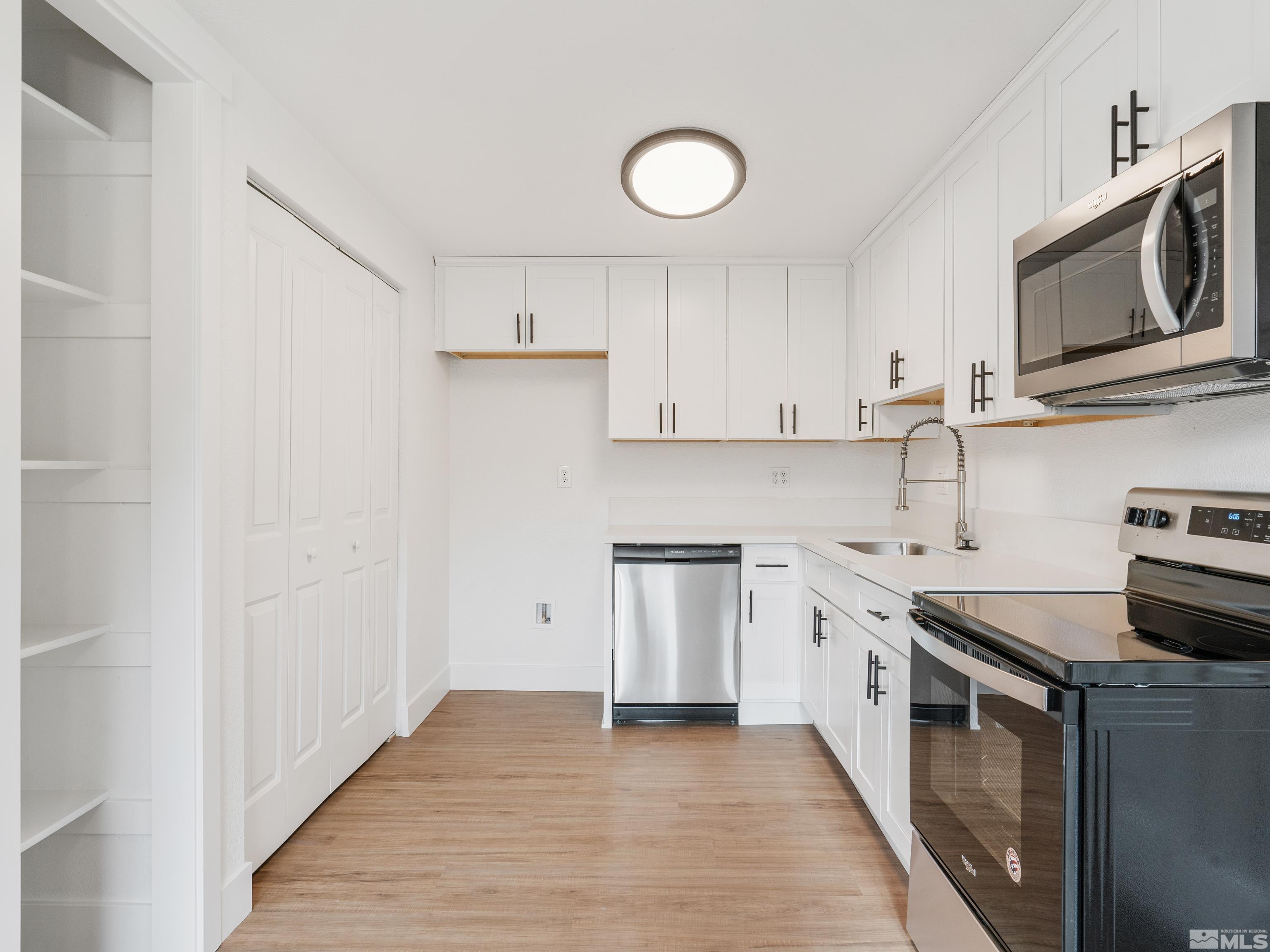 9485 Fremont Way Reno, NV 89506 - Photo 5 of 25 a kitchen with stainless steel appliances granite countertop a stove top oven a sink and dishwasher with white cabinets