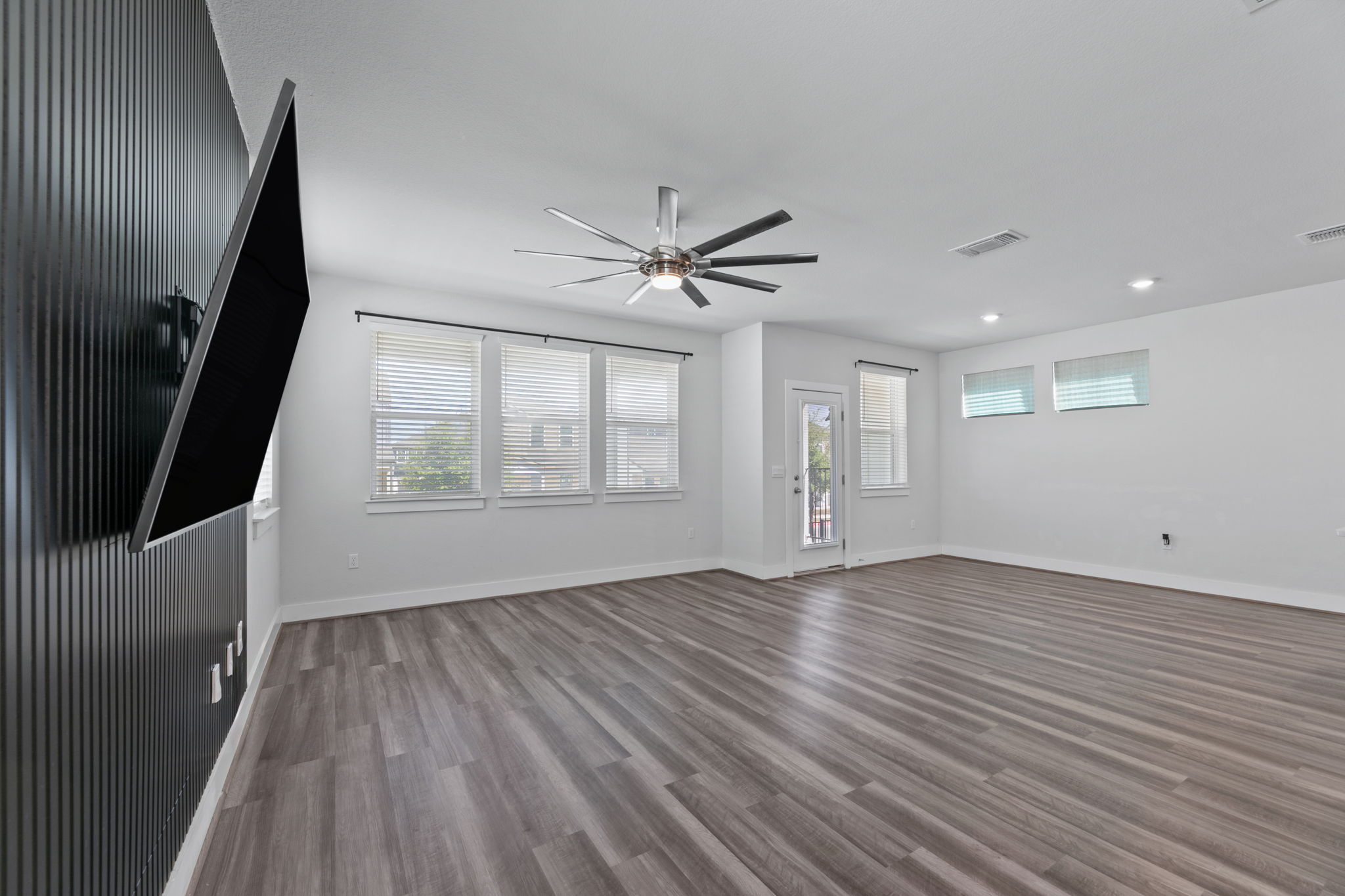 7312 Travertine Spring Drive Austin, TX 78744 - Photo 13 of 32 Bright, spacious great room features wide plank flooring and a modern ceiling fan.