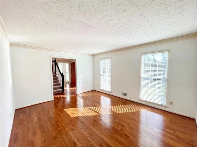 an empty room with wooden floor and windows