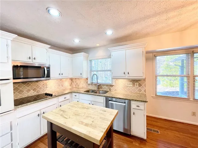 a kitchen with granite countertop a stove a sink and a refrigerator