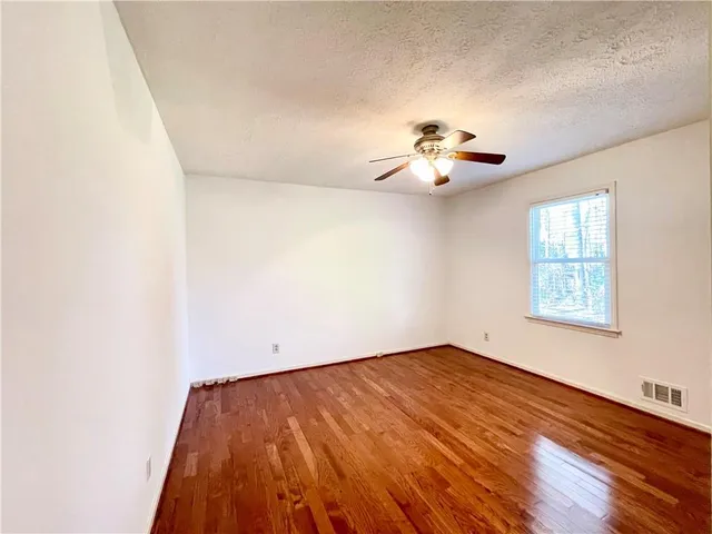 an empty room with a window and a ceiling fan