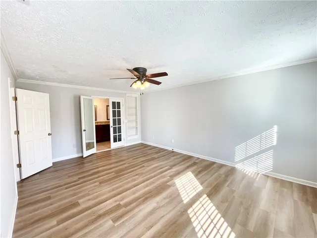 a view of empty room with wooden floor and fan