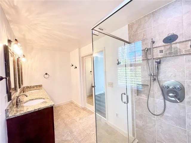 a bathroom with a granite countertop sink a mirror and shower