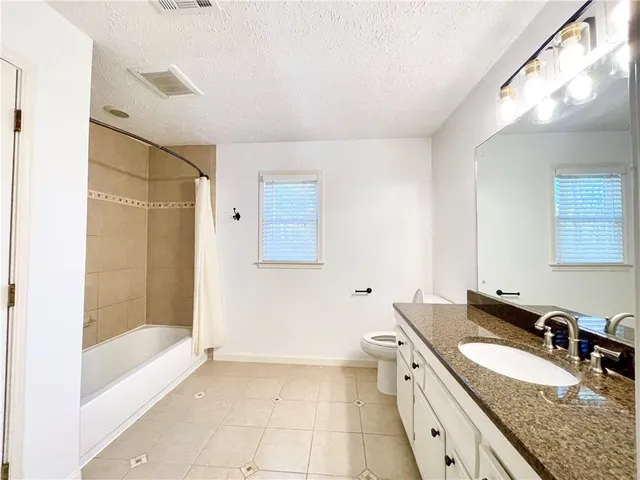a spacious bathroom with a granite countertop sink a toilet and shower
