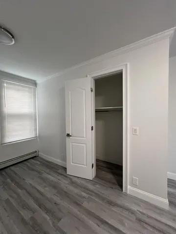 an empty room with wooden floor closet and windows