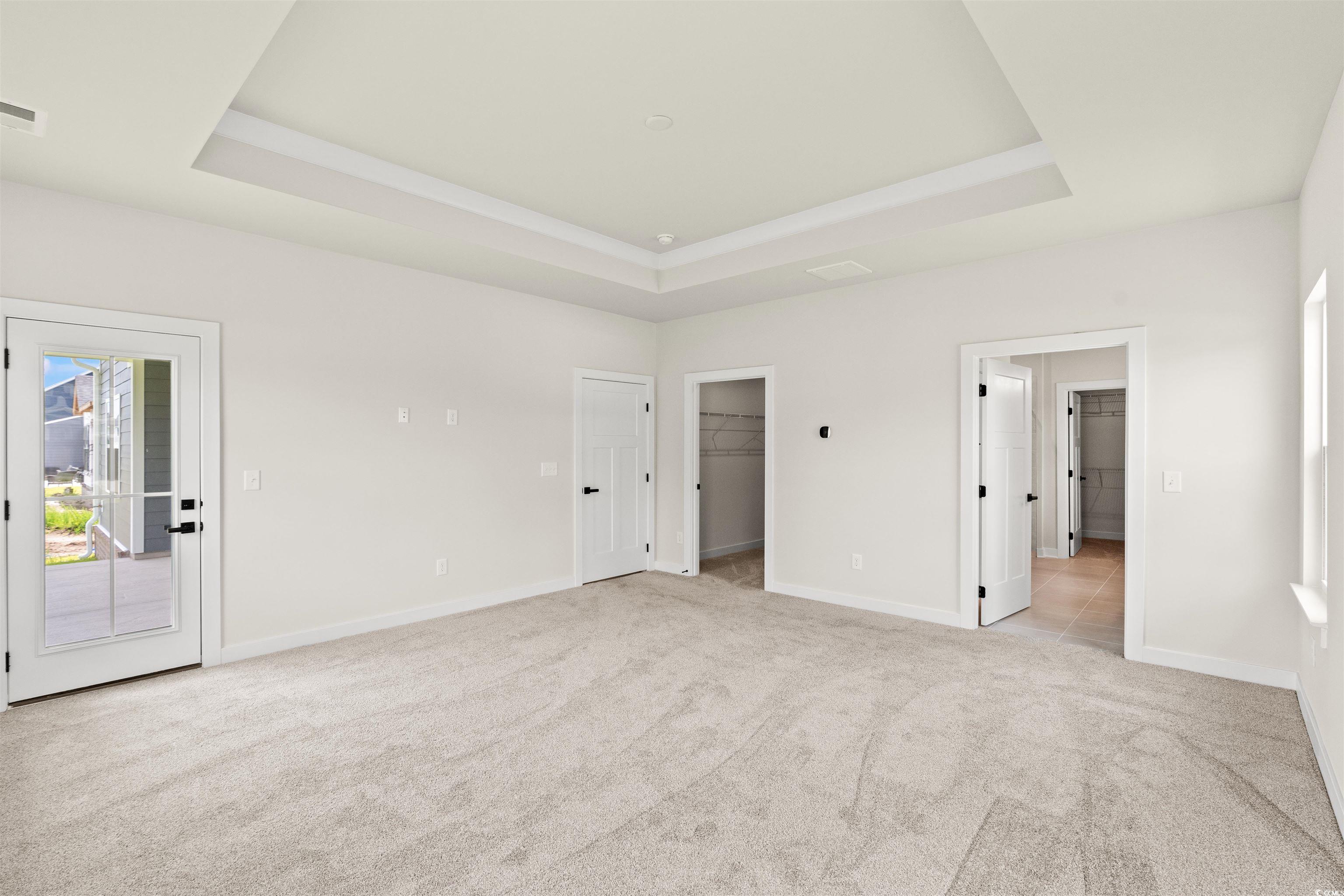 7076 Denim Loop Myrtle Beach, SC 29579 - Photo 14 of 27 Unfurnished bedroom with a walk in closet, a raised ceiling, carpet floors, and access to exterior